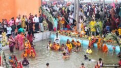 Chhath Puja 2026: घाट पर पानी में खड़े होकर पूजा करते छठ व्रती और किनारे भीड़